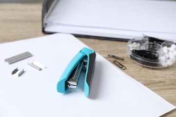 Stapler, paper and metal staples on table, closeup