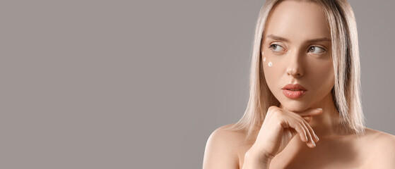 Naklejka premium Sexy young woman with cream on her face against grey background