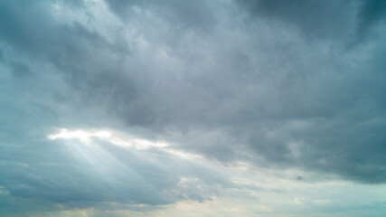 Naklejka na ściany i meble Sunbeam coming through a pocket in the clouds