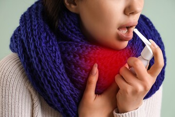 Ill young woman with inhaler on color background, closeup