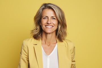 Portrait of smiling middle aged businesswoman looking at camera over yellow background
