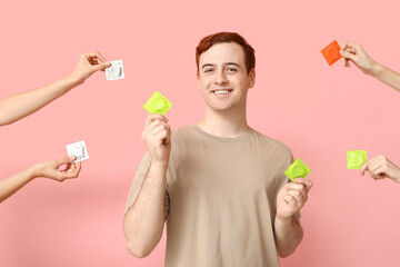 Young man and hands with condoms on pink background. Safe sex concept