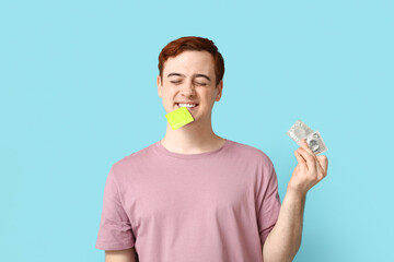 Funny young man with condoms on blue background. Safe sex concept