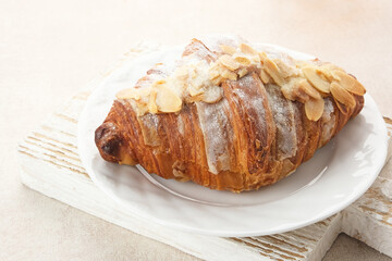 Almond Croissant with sprinkling icing sugar on white plate 
