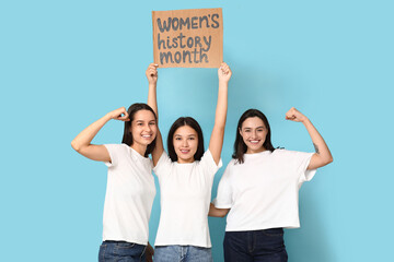 Beautiful women holding cardboard with text WOMEN'S HISTORY MONTH on blue background