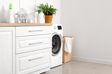 Interior of light room with washing machine and laundry basket