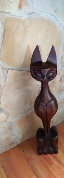 vintage (1960's) carved monkeypod wooden cat figure from the Philippines against a sandstone block wall
