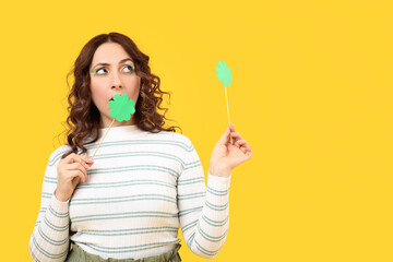 Woman with paper clover on yellow background. St. Patrick's Day