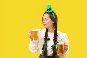 Happy woman with beer celebrating St. Patrick's Day on yellow background