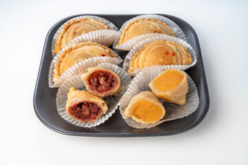Curry puffs purple and sweet potatoeon black plate on white background, Curry puff pastry on white background.