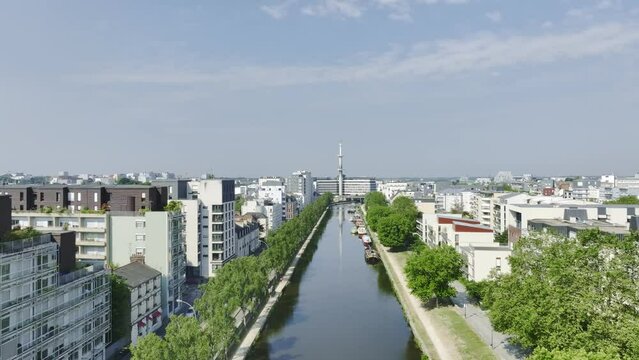 Aerial travelling drone shot of Rennes, Bretagne, France, quai de la Pr&eacute;valaye, le Mabilay. Scenic cityscape with sunny blue sky, river, quays, green trees, architecture, bird flying.