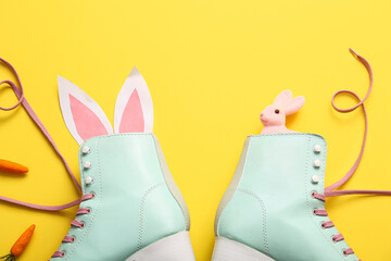 Vintage roller skates with bunny ears made of paper and carrots on yellow background. Easter...