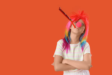 Funny girl in clown costume with party whistle on orange background. April Fool's Day celebration