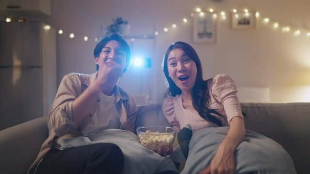 Asian young loving couple watch movie together in living room at home. 