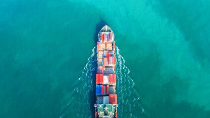 Aerial view of cargo ship with contrail in the ocean sea ship carrying container and running from...