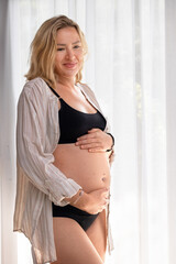 Portrait of a pregnant girl in a shirt and underwear