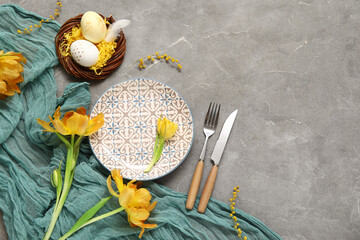 Table setting with Easter eggs, beautiful tulips and mimosa flowers on grey background - obrazy, fototapety, plakaty