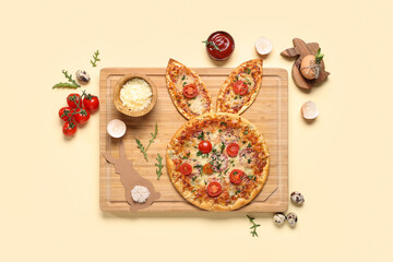 Board of tasty Easter pizza with bunny ears, sauce, cheese and tomatoes on yellow background
