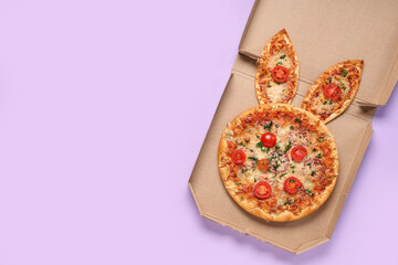 Cardboard box of Easter pizza with ears on lilac background