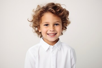 Portrait of a cute little boy with curly hair over gray background