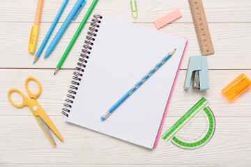 Notebook with scissors and stapler on white wooden background. Top view