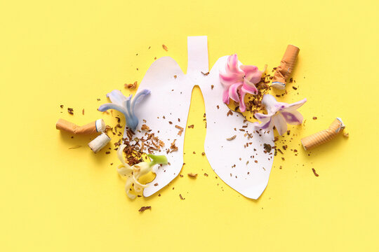 Paper lungs with scattered flowers, tobacco and cigarette butts on yellow background. Stop smoking concept.