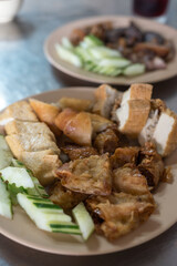 Fried tofu snack food served with raw cucumber slices and eaten with sweet and sour spicy sauce.