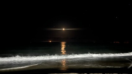 달이 화창하게 떠있는 파도가 치는 바다