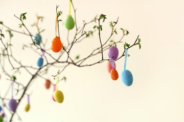 Tree branches with colorful Easter eggs on light background, closeup