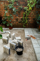 Concrete block floor construction work for courtyard patio as house exterior with green hanging...