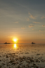 Golden Sunset Reflections. Tranquil beach scene with boats silhouetted against a colorful sky during sunset