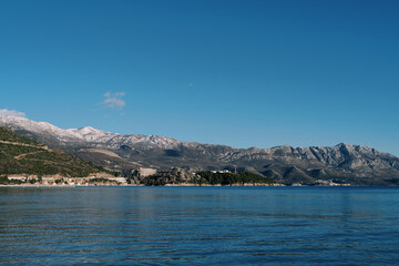 Fototapeta na wymiar Mountain range with snow-capped peaks on the seashore
