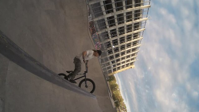 BMX rider tuck no hander huge air in skatepark bowl over spine in extreme slow motion, fisheye lens push in 800 fps