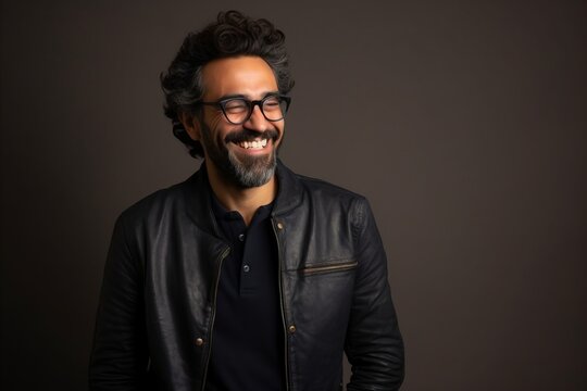 Portrait of a handsome bearded Indian man wearing black leather jacket and glasses