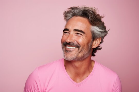 Portrait of happy mature man with grey hair and beard smiling at camera against pink background