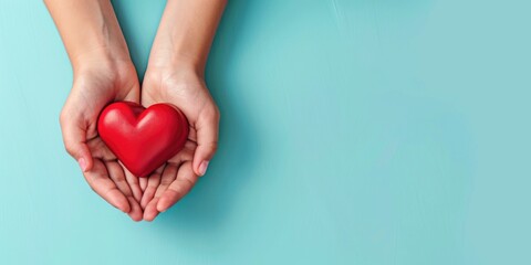 A person is holding a red heart in their hands