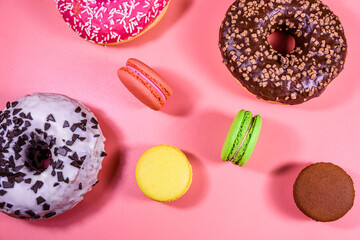 Fresh glazed donuts and french macaroons isolated on a pink background
