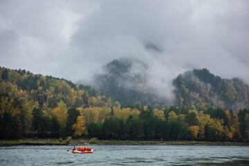 An inflatable rubber boat with rafters in red life jackets and yellow helmets are rafting on a...