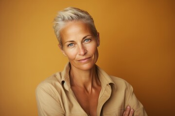Portrait of a beautiful middle aged woman with short blond hair against a yellow background