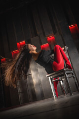 Beautiful young asian girl in black body wear red pantyhose is posing on dark iron wall background.