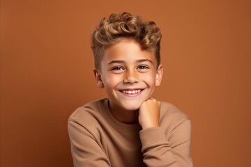 Portrait of a cute little boy smiling and looking at camera on brown background
