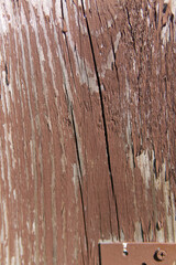 The texture of an old wooden board with peeling red paint. A vertical snapshot. Closeup
