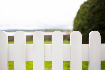 White wooden picket fence, in front of garden with sea view -  a home by the sea theme 