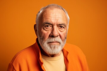 Portrait of an old man with gray beard and mustache on orange background