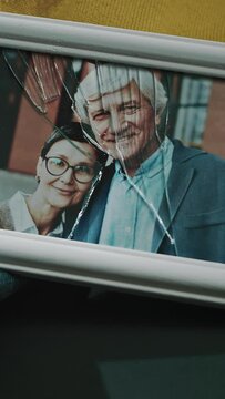 Vertical from above shot of broken picture frame of adult Caucasian married couple smiling at camera