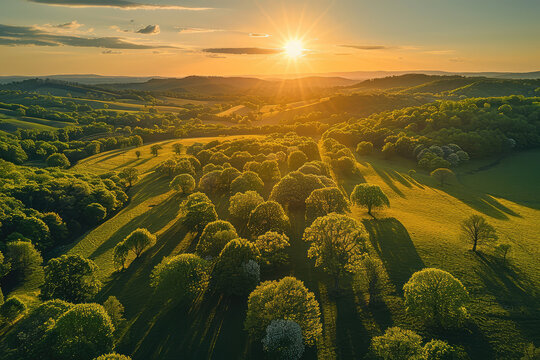 Beautiful aerial view of the English countryside with rolling hills and lush greenery at sunset. The sun sets in the background, casting long shadows over the landscape. Created with Ai