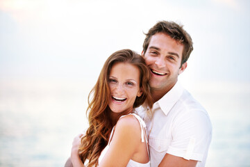Obraz premium Happy couple, portrait and holiday by ocean for love and travel on honeymoon adventure in sun. Man, woman and smile face for bonding in marriage, touch and together on beach vacation in cape town