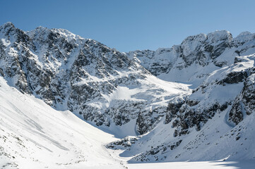 Szczyty otaczające Czarny Staw Gąsienicowy w polskich Tatrach sfotografowane w słoneczny zimowy dzień.