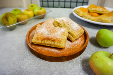 Homemade mini apple pie pastry placed on a plate with fresh apple in the background