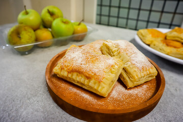 Homemade mini apple pie pastry placed on a plate with fresh apple in the background
